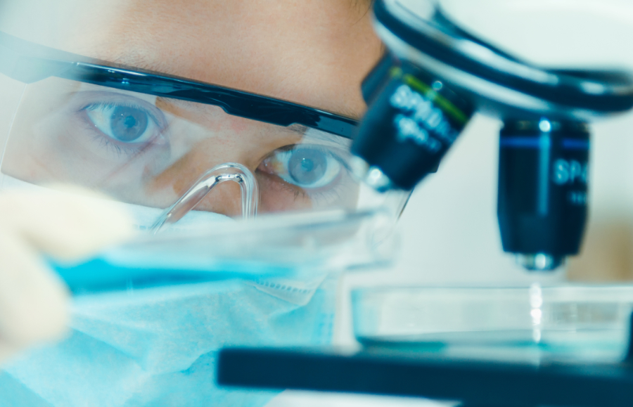 Scientist in goggles looking at a microscope