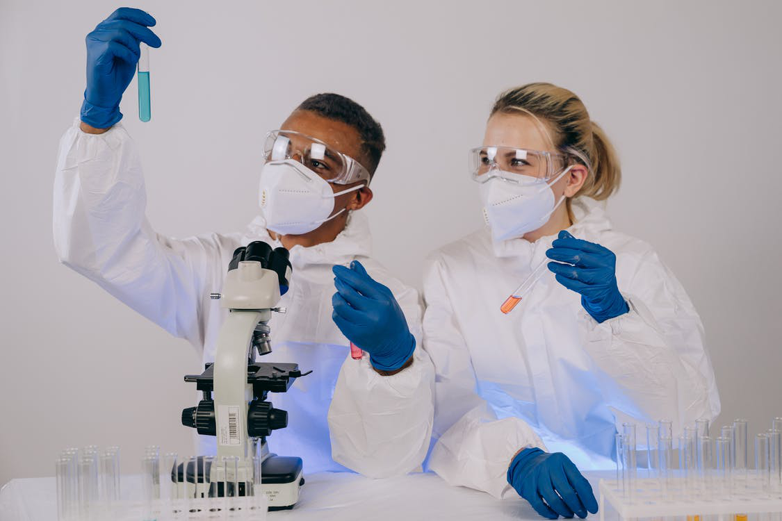 Two scientists look at a reagent vessel containing a blue liquid